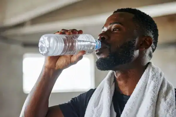Image of man drinking water to improve hydration Braintree after work out.